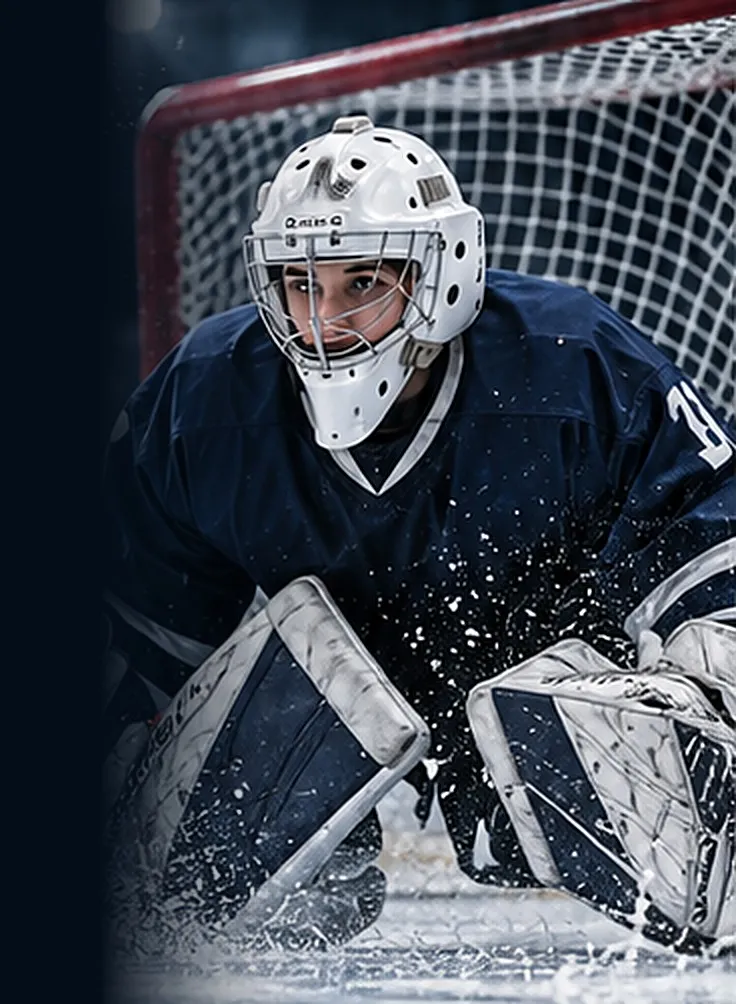 Hockey goaltender crouched in the crease, spraying ice
